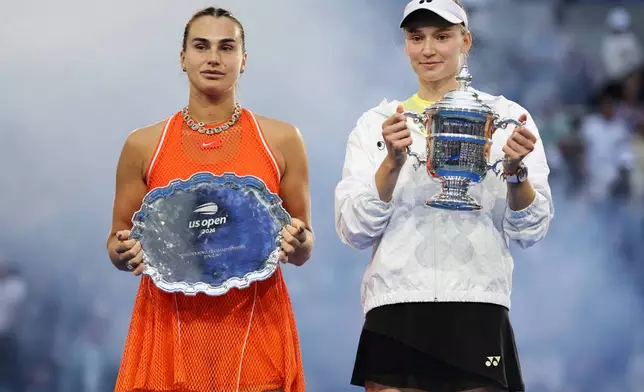 Aryna Sabalenka, of Belarus, left, and Elena Rybakina, of Kazakhstan, right, hold up their trophies after Rybakina won the women's singles final of the U.S. Open tennis championships Saturday, Sept. 12, 2026, in New York. (AP Photo/Adam Hunger)