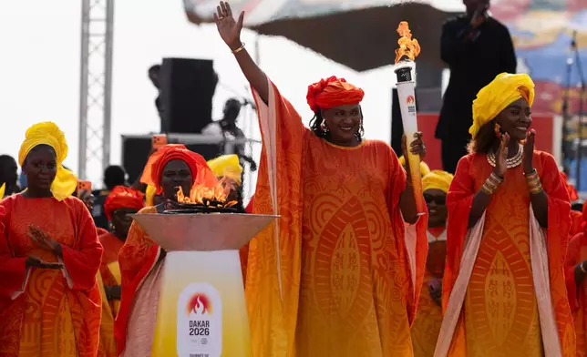 Senegalese basketball legend Mame Maty Mbengue lights a torch from the cauldron during a ceremony ahead of the Dakar 2026 Youth Olympic Games, in Dakar, Senegal, Saturday, Sept. 12, 2026. (AP Photo/Sylvain Cherkaoui)