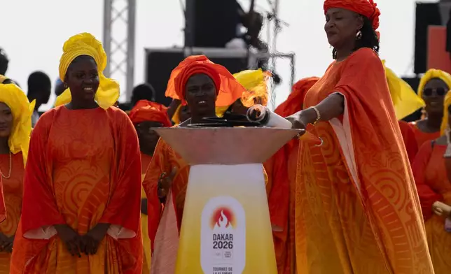 Senegalese basketball legend Mame Maty Mbengue lights a torch from the cauldron during a ceremony ahead of the Dakar 2026 Youth Olympic Games, in Dakar, Senegal, Saturday, Sept. 12, 2026. (AP Photo/Sylvain Cherkaoui)