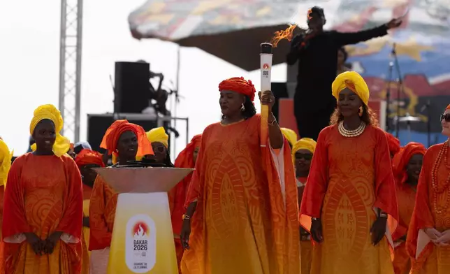 Senegalese basketball legend Mame Maty Mbengue lights a torch from the cauldron during a ceremony ahead of the Dakar 2026 Youth Olympic Games, in Dakar, Senegal, Saturday, Sept. 12, 2026. (AP Photo/Sylvain Cherkaoui)