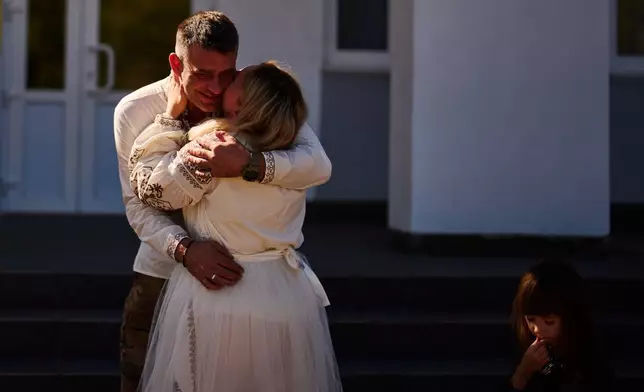 Liudmyla Ryzhak, right, kisses her fiancee Leonid Ryzhak before their wedding ceremony, following a Russian missile and drone attack, in Kyiv, Ukraine, Tuesday, Sept. 8, 2026. (AP Photo/Francisco Seco)