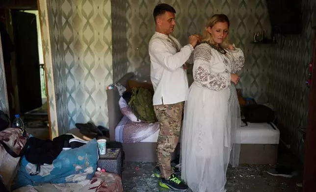 Liudmyla Ryzhak, right, and her fiancee Leonid Ryzhak get ready for their wedding ceremony in their damaged apartment, following a Russian missile and drone attack in Kyiv, Ukraine, Tuesday, Sept. 8, 2026. (AP Photo/Francisco Seco)