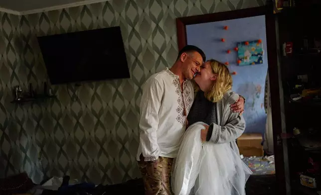 Liudmyla Ryzhak, right, and her fiancee Leonid Ryzhak get ready for their wedding ceremony in their damaged apartment, following a Russian missile and drone attack in Kyiv, Ukraine, Tuesday, Sept. 8, 2026. (AP Photo/Francisco Seco)