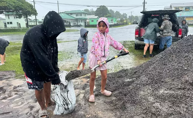 Kenzielynn Kekoa, center, of Hilo, Hawaii, helps her family fill sand bags as Hurricane Nolo approaches in Hilo, Hawaii, Friday, Sept. 25, 2026. (AP Photo/Eugene Garcia)