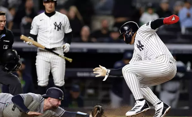 New York Yankees' George Lombard Jr. avoids a tag from Tampa Bay Rays catcher Liam Hicks to score a run during the seventh inning of a baseball game Thursday, Sept. 24, 2026, in New York. (AP Photo/Adam Hunger)