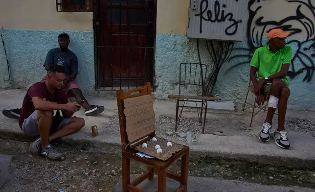 People hang out near eggs for sale on a street during a blackout in Havana, Cuba, Friday, Sept. 18, 2026. (AP Photo/Ramon Espinosa)