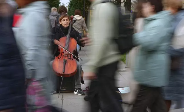 People walk past a street musician playing the cello in St. Petersburg, Russia, Wednesday, Sept. 23, 2026. (AP Photo/Dmitri Lovetsky)