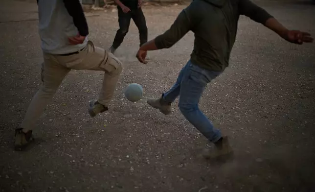 Members of a Palestinian-Bedouin community play soccer on the outskirts of the West Bank town of Taybeh, Thursday, Sept. 24, 2026, after Israeli settlers walked with their animals past their compound toward a nearby outpost. (AP Photo/Leo Correa)