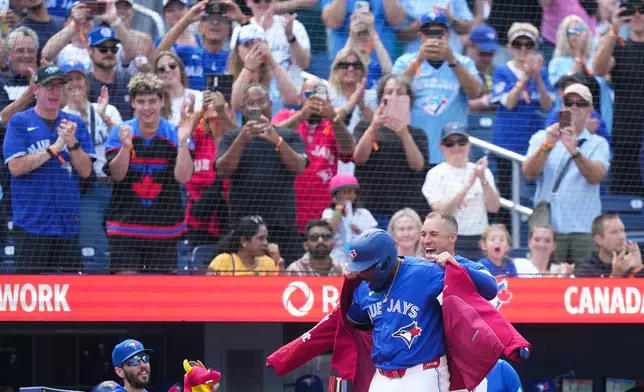 Toronto Blue Jays' Vladimir Guerrero Jr., front left, gets the home run jacket put on by teammate George Springer, front right, after hitting a solo home run against the Baltimore Orioles during the fifth inning of a baseball game in Toronto, Sunday, Sept. 13, 2026. (Nathan Denette/The Canadian Press via AP)