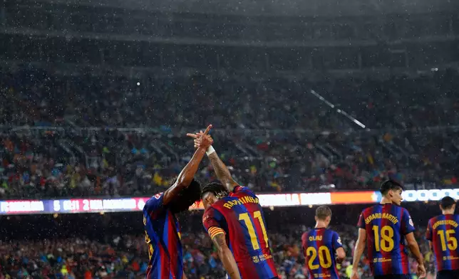 Barcelona's Raphinha celebrates with Lamine Yamal, left, after scoring his side's fifth goal from the penalty spot during a Spanish La Liga soccer match between Barcelona and Racing de Santander in Barcelona, Spain, Wednesday, Sept. 16, 2026. (AP Photo/Joan Monfort)