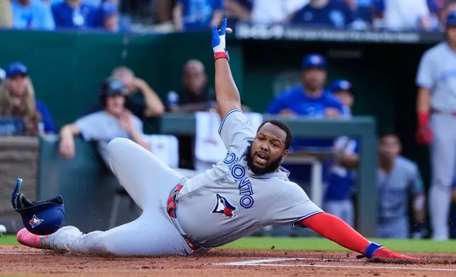 Toronto Blue Jays' Vladimir Guerrero Jr. beats the tag at home by Kansas City Royals catcher Carter Jensen to score on a single by Alejandro Kirk during the first inning of a baseball game Saturday, Sept. 5, 2026, in Kansas City, Mo. (AP Photo/Charlie Riedel)