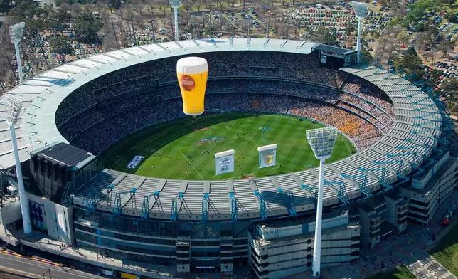 FILE - A hot air balloon shaped as a drinking glass flies over the Melbourne Cricket Ground in Melbourne, Australia, on Sept. 27, 2008. (AP Photo/Andrew Chapman, File)