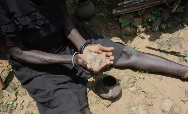 A rainmaker from a village in the Lopit Mountains shows sacred stones used in rainmaking rituals, South Sudan, Thursday, July 24, 2025. (AP Photo/Joseph Falzetta)