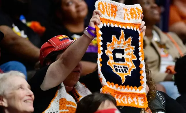 Connecticut Sun fan Adrianna Wilkinson, center left, of Brockton, Mass., holds up a handmade sign in the first half of a WNBA basketball game against the Toronto Tempo, Thursday, Sept. 24, 2026, in Uncasville, Conn. (AP Photo/Jessica Hill)