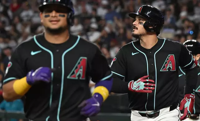 Arizona Diamondbacks' Gabriel Moreno, left, and Nolan Arenado, right, run back toward the dugout after scoring on Arenado's grand slam in the fifth inning of a baseball game against the New York Yankees, Sunday, Sept. 20, 2026, in Phoenix. (AP Photo/Caitlin O'Hara)