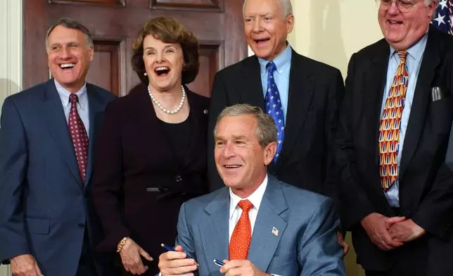 FILE - President George W. Bush shares a laugh with, from left, Sen. Jon Kyl, R-Ariz., Sen. Dianne Feinstein, D-Calif., Sen. Orrin Hatch, R-Utah, and Sen. James Sensenbrenner, R-Wis., after signing a bill into law, July 15, 2004, in the Roosevelt Room of the White House. (AP Photo/Susan Walsh, File)