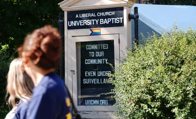 People walk by a sign outside University Baptist Church, Friday, Sept. 4, 2026, in Minneapolis. (AP Photo/Ellen Schmidt)