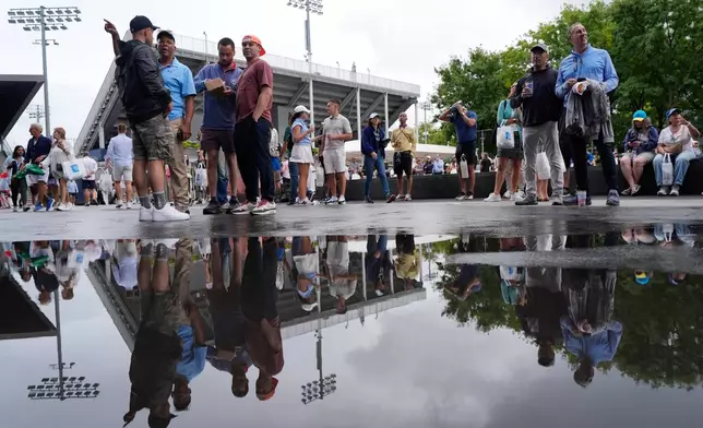 Spectators are reflected in a puddle at the USTA Billie Jean King National Tennis Center during the U.S. Open tennis championships Wednesday, Sept. 2, 2026, in New York. (AP Photo/Seth Wenig)