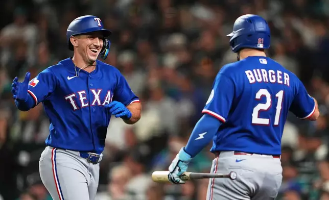 Texas Rangers' Wyatt Langford, left, celebrates his two-run home run with teammate Jake Burger (21) during the fifth inning of a baseball game against the Seattle Mariners, Tuesday, Sept. 8, 2026, in Seattle. (AP Photo/Lindsey Wasson)
