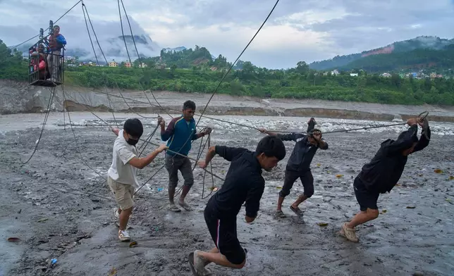 FILE - Residents commute across the Trishuli River on a newly installed zipline in the aftermath of flash floods at Bidur, Nuwakot district, Nepal, Sept. 5, 2026. (AP Photo/Niranjan Shrestha, File)