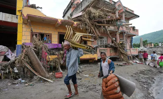FILE - Residents leave with belongings salvaged from their flood-damaged homes in Devighat, in Nepal's Nuwakot district, Aug. 29, 2026. (AP Photo/Rajesh Kumar Singh, File)