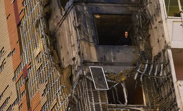 A woman peers from a window of a partially damaged residential building following a Russian drone attack in Kyiv, Ukraine, Wednesday, Sept. 9, 2026. (AP Photo/Francisco Seco)