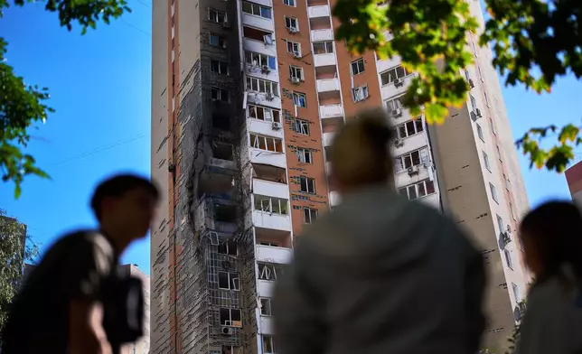 Locals watch as firefighters work on a partially damaged residential building following a Russian drone attack in Kyiv, Ukraine, Wednesday, Sept. 9, 2026. (AP Photo/Francisco Seco)
