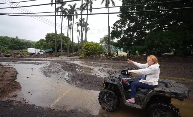 Peggy McKibbin looks at where floodwaters from nearby Hurricane Nolo run past widespread damage from last month's Hurricane Lala Sunday, Sept. 27, 2026, in Naalehu, Hawaii. (AP Photo/Gregory Bull)
