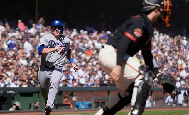 Los Angeles Dodgers' Will Smith, left, runs home to score against San Francisco Giants catcher Andrew Knizner during the fourth inning of a baseball game, Saturday, Sept. 26, 2026, in San Francisco. (AP Photo/Jeff Chiu)