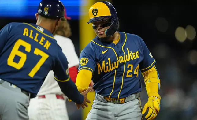 Milwaukee Brewers' William Contreras celebrates his hits a two-run single off of Philadelphia Phillies pitcher Aaron Nola with teammate first base coach Spencer Allen during the third inning of a baseball game, Wednesday, Sept. 23, 2026, in Philadelphia. (AP Photo/Matt Rourke)
