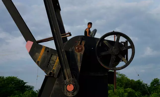A boy sits on an inactive oil pumpjack in Cabimas, Venezuela, Monday, Aug. 31, 2026. (AP Photo/Ariana Cubillos)