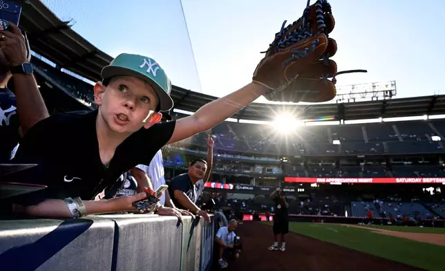 A fan tries to get the attention of New York Yankees' Aaron Judge for an autograph before a baseball game against the Los Angeles Angels, Monday, Aug. 31, 2026, in Anaheim, Calif. (AP Photo/Wally Skalij)