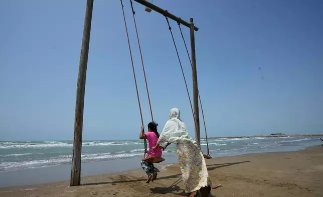 A woman pushes a girl on a swing on a beach along the Strait of Hormuz in Kuhestak, Iran, Friday, Sept. 4, 2026. (AP Photo/Vahid Salemi)