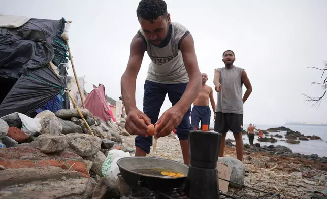 Migrants cook near their tents at El Trampolín beach in the Spanish exclave of Ceuta, Wednesday, Sept. 2, 2026. (AP Photo/Francis González)
