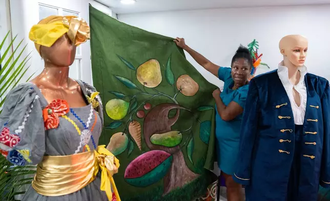 Haitian-born Clara Poteau holds up a Haitian costume for Lespri Ayiti Mas Camp, ahead of the West Indian Day Parade, Thursday, Sept. 3, 2026, in the Brooklyn borough of New York. (AP Photo/Adam Gray)