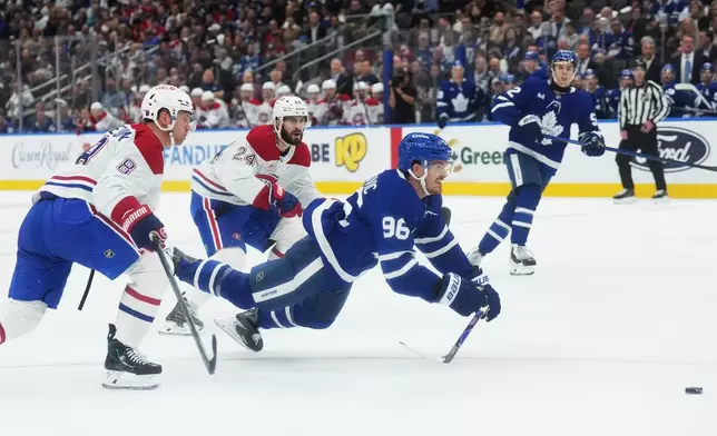 Toronto Maple Leafs' Jack Roslovic (96) gets tripped up by Montreal Canadiens' Mike Matheson (8) and Phillip Danault (24) during the second period of an NHL hockey game against the Montreal Canadiens in Toronto, Tuesday, Sept. 29, 2026. (Nathan Denette/The Canadian Press via AP)