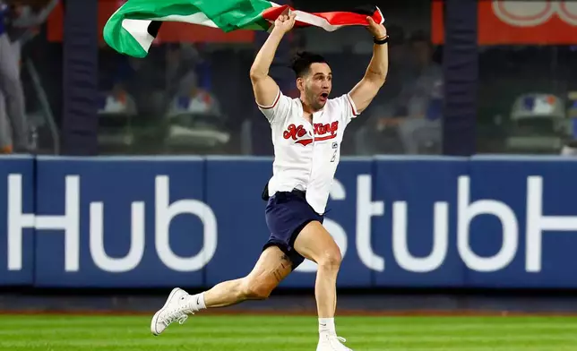 A fan waving a Palestinian flag runs in the outfield during the seventh inning of a baseball game between the New York Yankees and the New York Mets, Friday, Sept. 11, 2026, in New York. (AP Photo/Noah K. Murray)