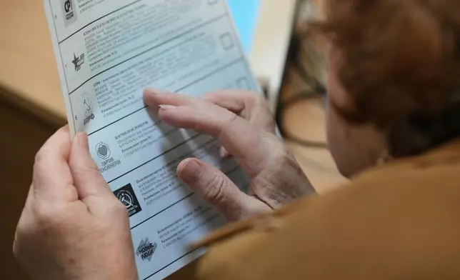 A voter looks through a ballot during the parliamentary election in Moscow, Sunday, Sept. 20, 2026. (AP Photo/Pavel Bednyakov)