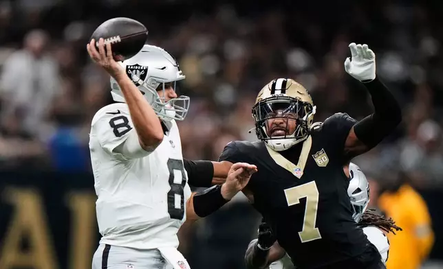 Las Vegas Raiders quarterback Kirk Cousins (8) throws a pass under pressure from New Orleans Saints safety Jonas Sanker (7) during the first half of an NFL football game in New Orleans, Sunday, Sept. 27, 2026. (AP Photo/Gerald Herbert)