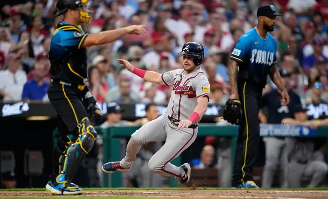 Atlanta Braves' Lane Thomas, center, scores past Philadelphia Phillies catcher J.T. Realmuto, left, and pitcher Cristopher Sánchez on a single by Austin Riley during the second inning of a baseball game Friday, Sept. 4, 2026, in Philadelphia. (AP Photo/Matt Slocum)