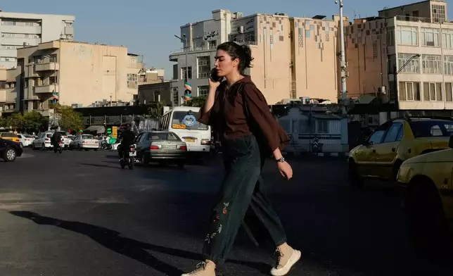 A woman talks on her cellphone as she walks across the Islamic Revolution square in downtown Tehran, Tuesday, Sept. 15, 2026. (AP Photo/Vahid Salemi)
