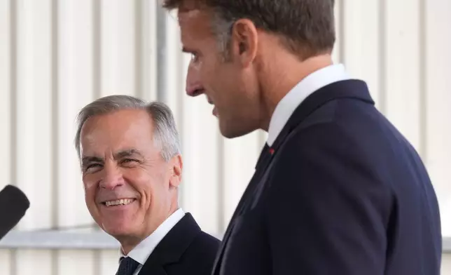 Canadian Prime Minister Mark Carney, left, reacts to French President Emmanuel Macron as he delivers remarks in Saint-Pierre, Saint-Pierre-et-Miquelon, Sunday, Sept.20, 2026. (Adrian Wyld/The Canadian Press via AP)