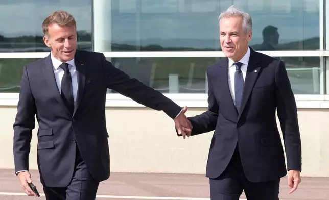 French President Emmanuel Macron, left, leads Canadian Prime Minister Mark Carney to his plane after the leaders delivered remarks in Saint-Pierre, Saint-Pierre-et-Miquelon, Sunday, Sept.20, 2026. (Adrian Wyld/The Canadian Press via AP)