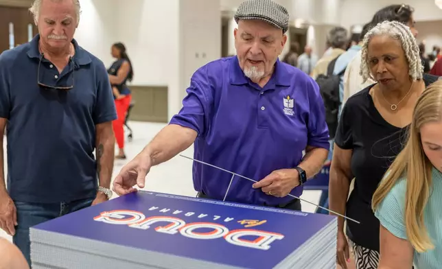 FILE - Michael Davis, of Bellwood, Ala., picks up a sign supporting Doug Jones for governor after a town hall hosted by Troy University College Democrats and the Pike County Democrats, Aug. 18, 2026, in Troy, Ala. (AP Photo/Vasha Hunt, File)