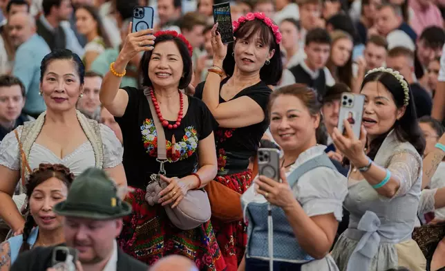 Visitors take pictures of the Oktoberfest parade at the 191st Oktoberfest beer festival in Munich, Germany, Saturday, Sept.19, 2026. (AP Photo/Matthias Schrader)