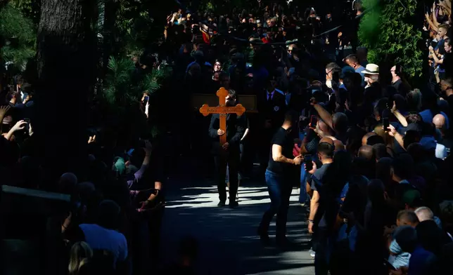 A young man carries the cross of the former Bosnian Serb army commander Ratko Mladic, who died last week while serving a life sentence for genocide and other atrocities during the war in Bosnia, at the Topcider Cemetery, in Belgrade, Serbia, Monday, Sept. 7, 2026. (AP Photo/Marko Drobnjakovic)