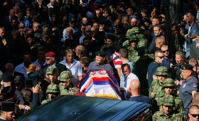 Serbian national military servicemen walk by the coffin of the former Bosnian Serb army commander Ratko Mladic, who died last week while serving a life sentence for genocide and other atrocities during the war in Bosnia, at the Topcider Cemetery, in Belgrade, Serbia, Monday, Sept. 7, 2026. (AP Photo/Marko Drobnjakovic)