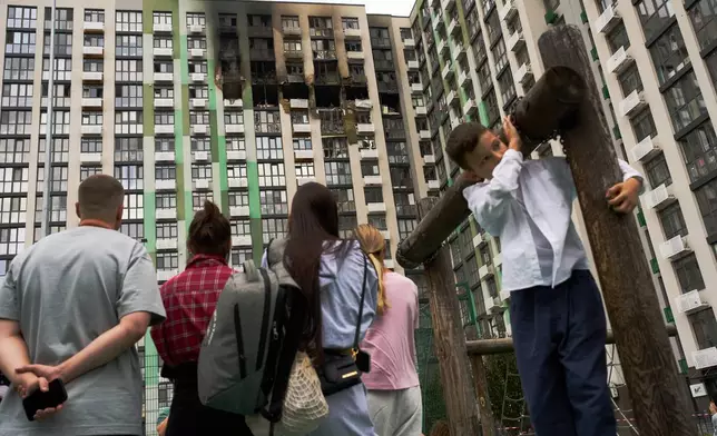 Locals watch as firefighters work after a Russian drone attack struck a residential building in Kyiv, Tuesday, Sept. 1, 2026. (AP Photo/Francisco Seco)