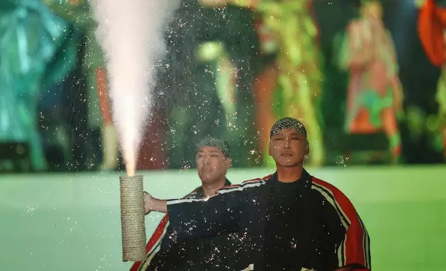 A performer shows the tezutsu fireworks during the opening ceremony for the Asian Games in Nagoya, Japan, Saturday, Sept. 19, 2026. (AP Photo/Lee Jin-man)