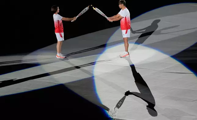 Japan's Akari Fujinami, left, and Kosuke Kitajima gesture with their torches before the lighting of the cauldron during the opening ceremony for the Asian Games in Nagoya, Japan, Saturday, Sept. 19, 2026. (AP Photo/Dita Alangkara)